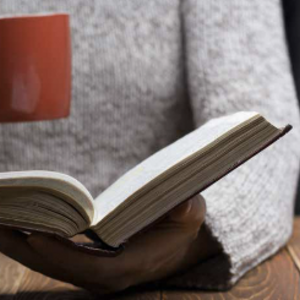 Frau mit Kaffee und Buch in der Hand