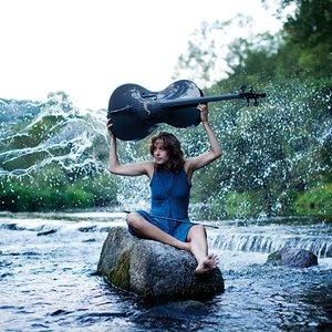 Sophie Abraham mit Ihrem Cello sitzend auf einem Stein, in einem tosenden Fluss. Foto von Julia Wesely