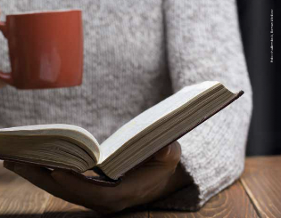 Frau mit Kaffee und Buch in der Hand